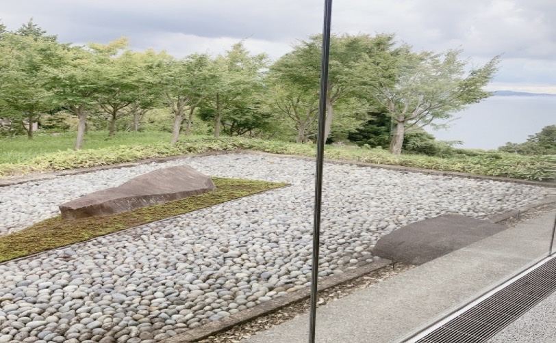 庭石と白い小石が敷き詰められた日本庭園の風景 海が見える
