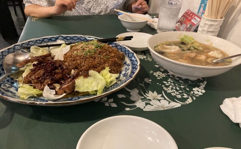 皿に盛られた豚肉料理と炒飯風のご飯、大きな丼に入った麺料理