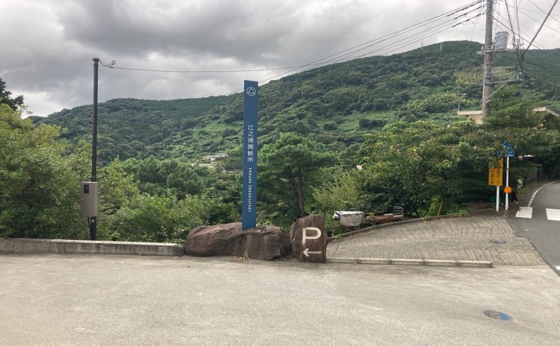 江之浦測候所の看板と駐車場への案内がある風景