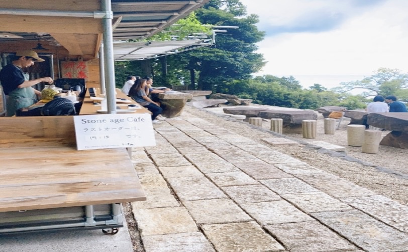 石畳の道にあるカフェでくつろぐ人たちと周囲の自然の風景