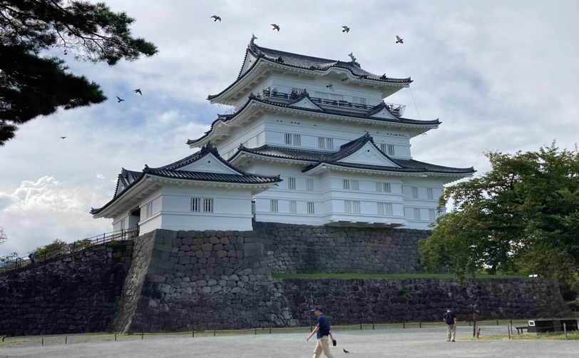 白い壁の弘前城と石垣を歩く人々