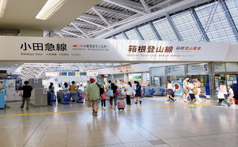 小田急線と箱根登山線の駅の改札を通る人々