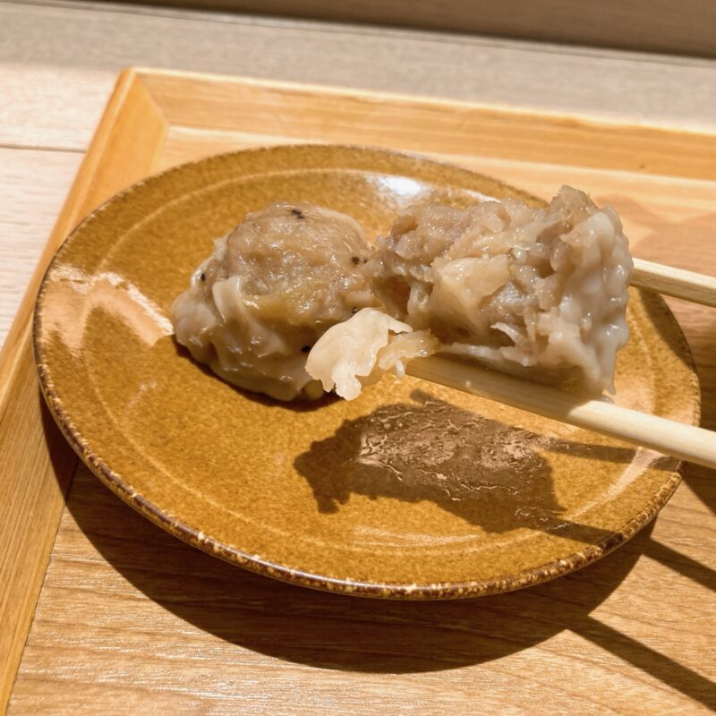 お皿にのった箸でつまんだ焼売