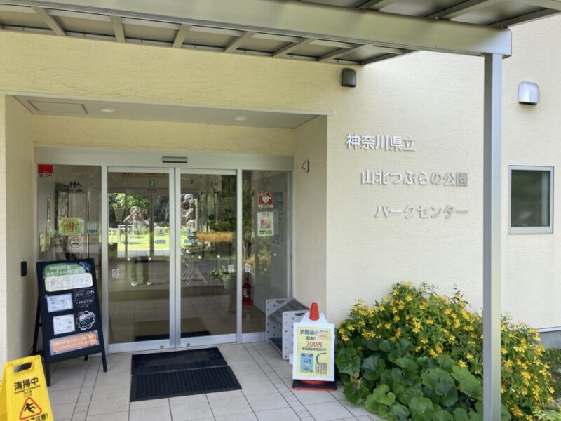神奈川県立山北つぶらの公園パークセンターの建物入口に自動ドアと案内板と黄色い花壇