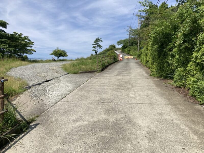 山の上の道で、向こうに白いゲートとオレンジのコーンがある