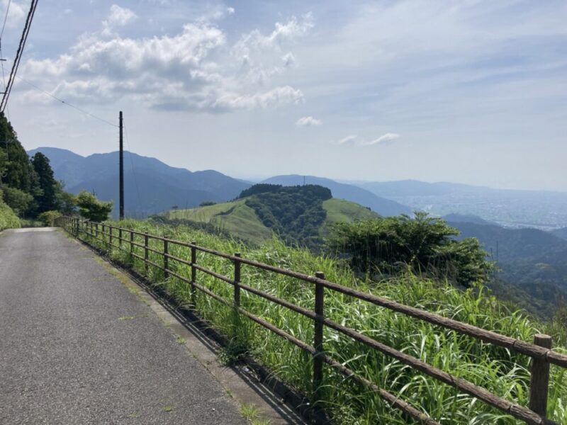 山の上の道と草原遠くに街並みが見える景色