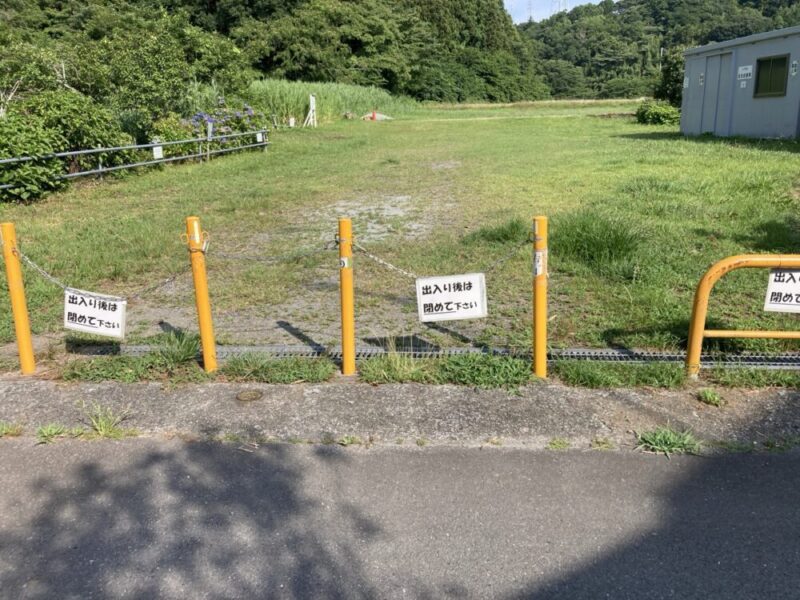 黄色い棒に囲まれた空き地に「出入り後は閉めて下さい」と書かれた白い看板が掛かっている様子