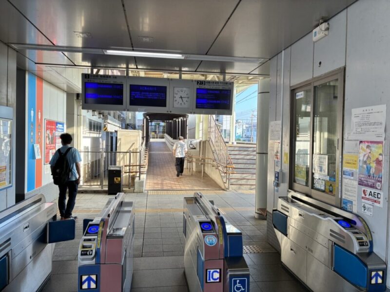 駅の改札口に立つ人たちと電車案内板
