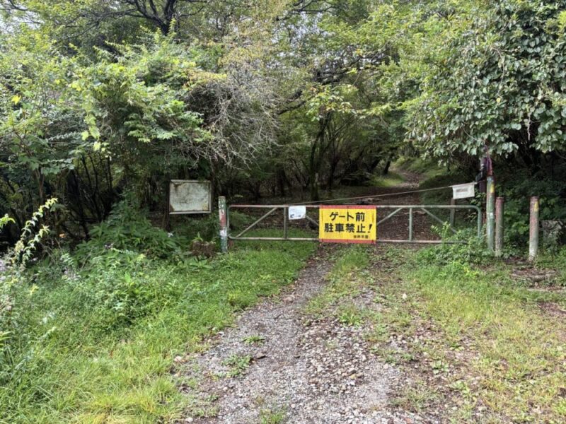 山道のゲート前に駐車禁止の看板がある風景