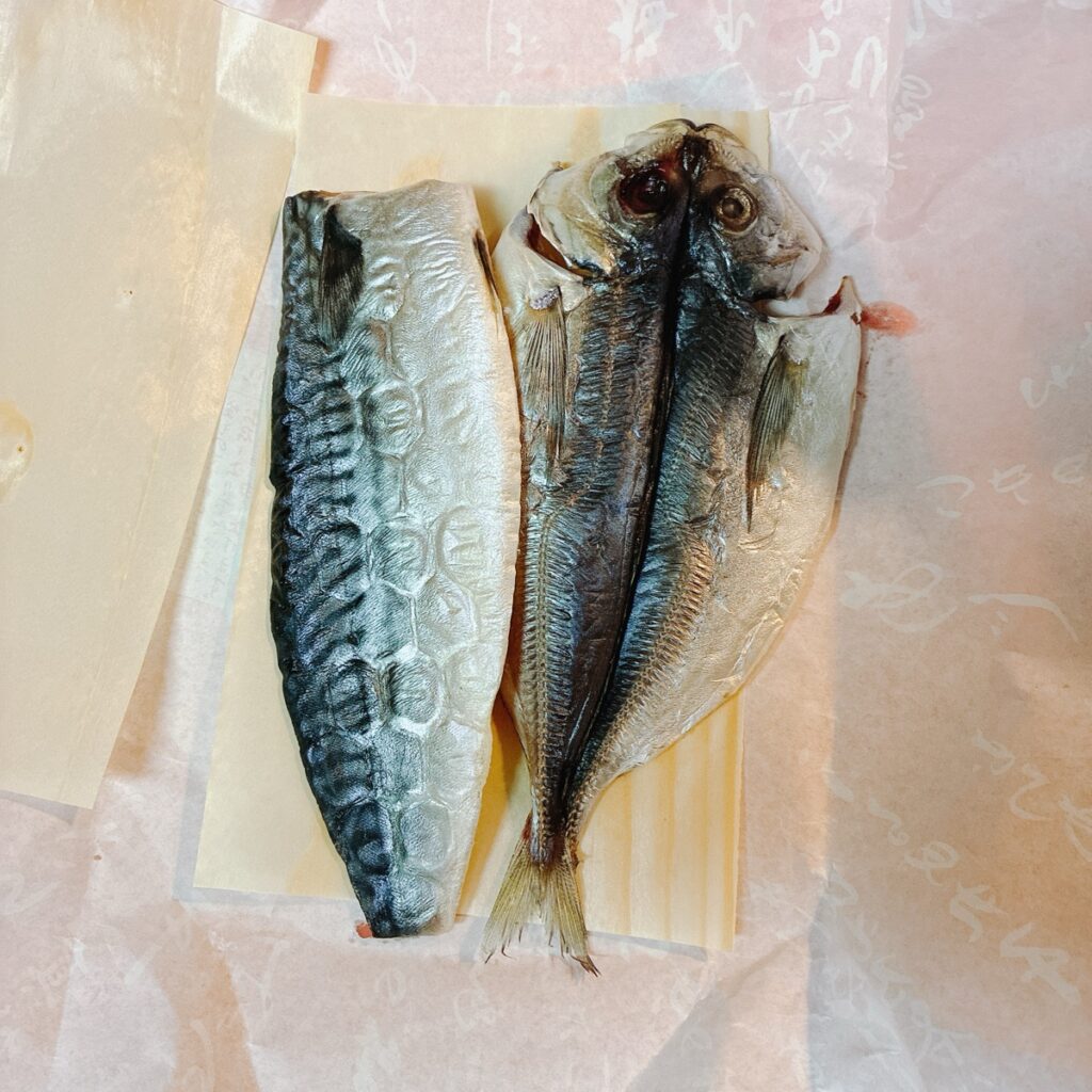 薄い紙の上に置かれた鯖の半身とアジの開き
