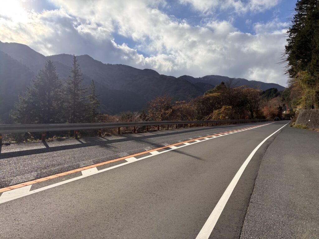 ガードレールと紅葉の木々が並ぶ秋の山道