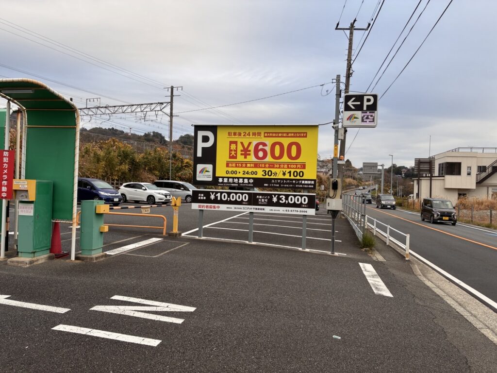 ユニマットパーキング藤が丘の入り口と24時間最大料金600円の看板 奥に道路と線路