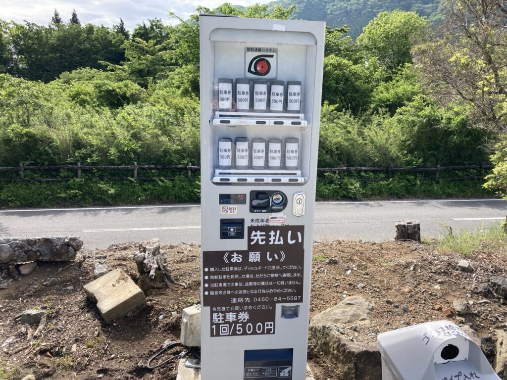 山道沿いに立つ駐車券自動販売機 料金500円と利用案内