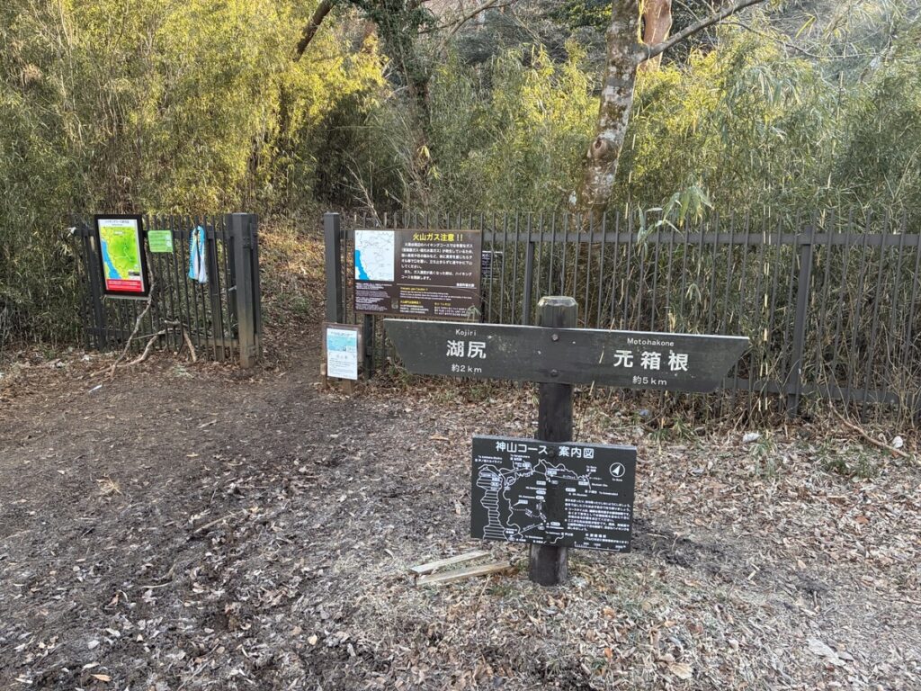 登山道の入口にある木製道標が湖尻へ約2km元箱根へ約5kmを示す火山ガス注意と神山コース案内図の看板も見られる