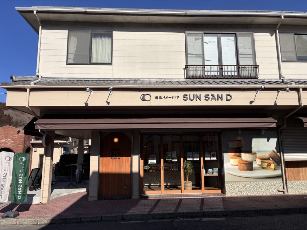 SUN SANDと書かれたパン屋の店舗外観 青空と窓のサンドクッキーの写真