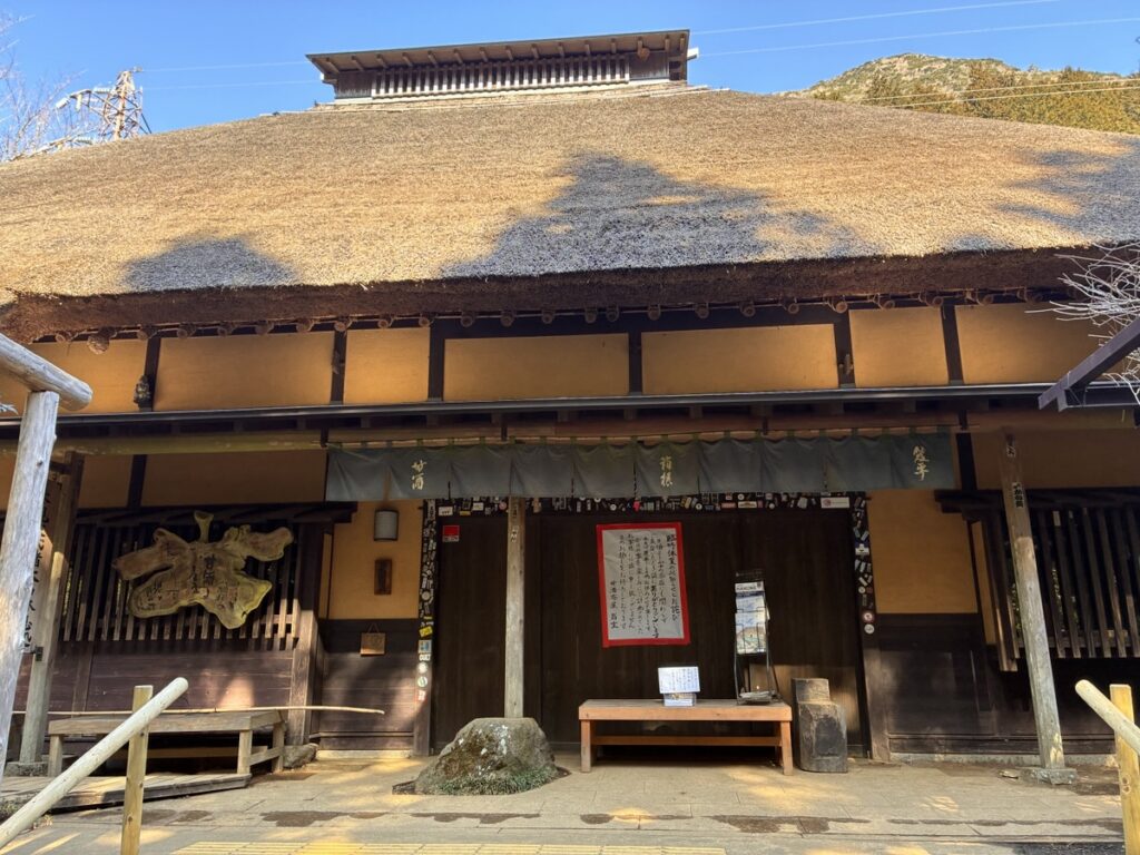 甘酒 稲荷 賀茂の暖簾がある茅葺き屋根の建物
